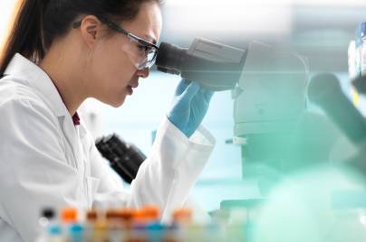 Scientists viewing microscope sample in lab