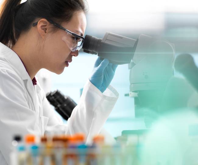 Scientists viewing microscope sample in lab
