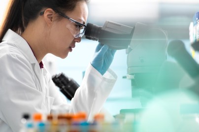 Scientists viewing microscope sample in lab