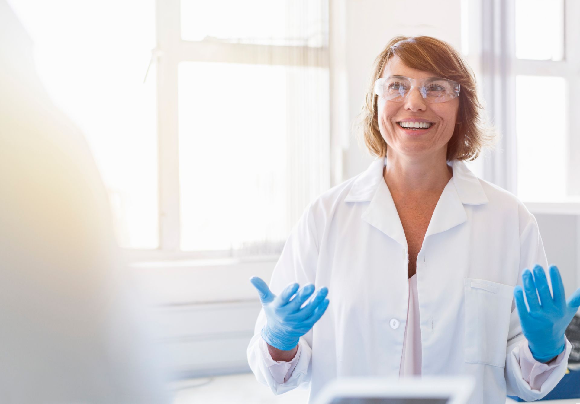 Happy chemist gesturing and talking in laboratory