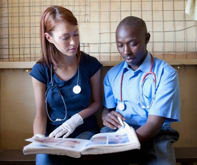 Two doctors studying medical book in clinic, Kenya