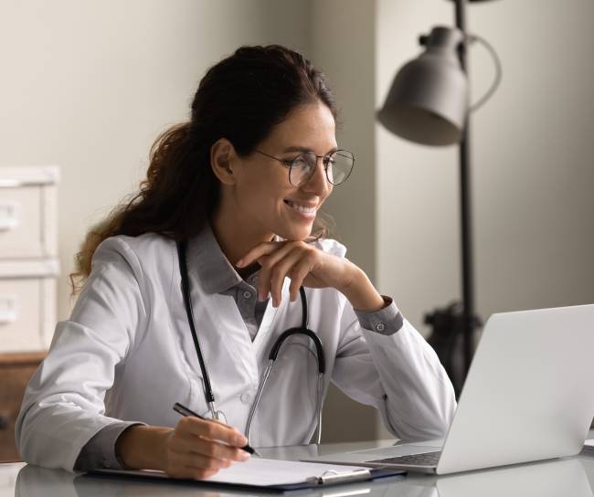 Smiling,Professional,Female,Doctor,Wearing,Glasses,And,Uniform,Taking,Notes